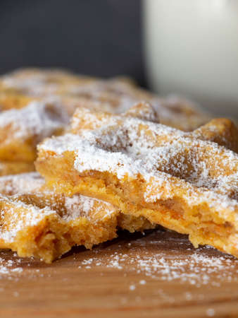 crushed carrot waffle dusted with icing sugar on a wooden plateの写真素材