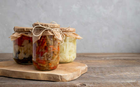 Jars of home-made fermented vegetables. Pickled, salted paprika, carrot, cauliflower and cucumbers. Place for text. Homemade blanks.の写真素材