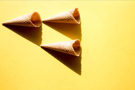 Three empty waffle cups on a yellow background in bright sunlight and crisp, hard shadowsの写真素材