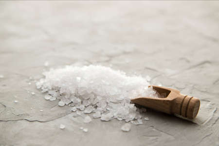 Sea salt crystals in wooden scoop close-up on concrete background. Small shovel with sea salt. Place for textの写真素材