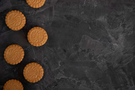 round shortbread cookies with a layer of cream on a dark background are laid out in a vertical line. Place for textの写真素材