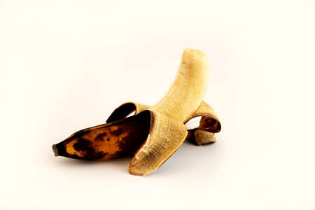Overripe half-peeled banana on a white backgroundの写真素材