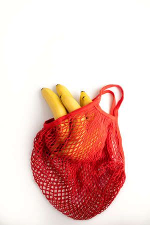 A bunch of yellow bananas in a red cotton string bag on a white background, top view. Zero waste. The concept of conservation of nature on the planet.の写真素材