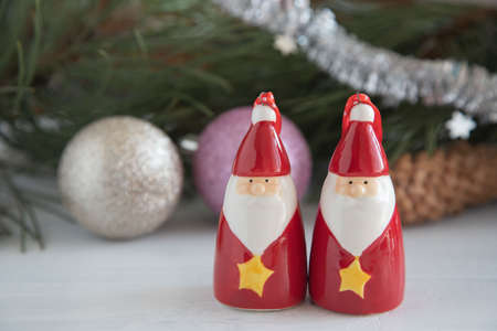 two ceramic figures of Santa Clauses, Christmas decorations for the Christmas tree. New Year's toys on a white wooden backgroundの写真素材
