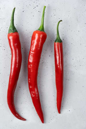 Three red fresh hot organic chili peppers lie on a concrete tableの写真素材
