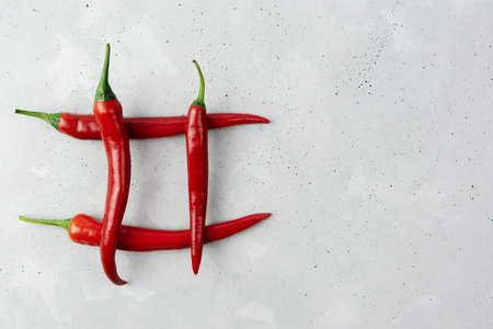Red chili pepper lies on a concrete gray table in the form of cells, lattice. Copy space.の写真素材