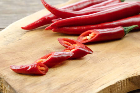 Close-up of hot chili peppers, paprika cut into pieces on a wooden board.の写真素材