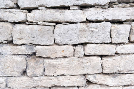 A fragment of a gray stone wall from sloppy stones, cobblestones of various sizes. Ideal for wallpapers, backgrounds and textures.の写真素材