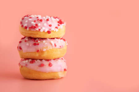 Three donuts with pink icing and raspberry decoration lie on each other against a pastel pink, coral color. Place for text. Food, morning, junk food, sweet life.の写真素材