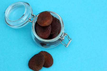 Organic dried apricots, dried apricots in a glass jar on a blue background. Healthy snack. Dried fruits. Place for textの写真素材