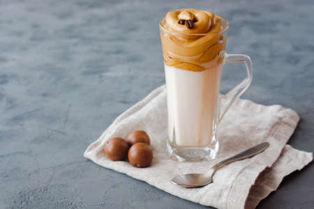 A glass with a trendy cold Dalgon coffee drink stands on a linen napkin, next to a teaspoon and chocolates. Copy space.の写真素材