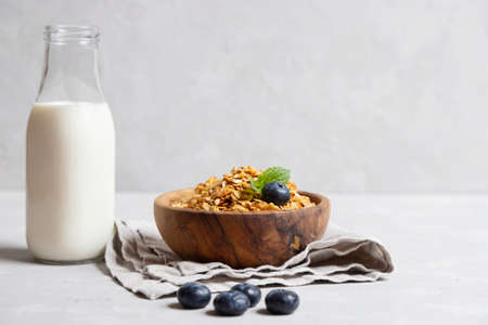 Homemade cooked healthy granola for breakfast in a wooden bowl on the table and near a bottle of milk. Place for text. Fitness food, snack.の写真素材