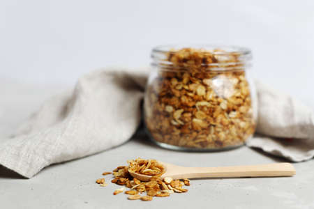 a glass jar full of oatmeal granola, in the foreground a wooden spoon with granola. Healthy breakfast on the right diet, diet. Place for text. Fitness breakfast.の写真素材