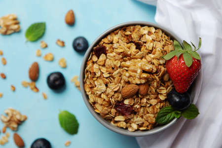 A bowl, a cup of freshly made oatmeal granola stands on a table decorated with berries. Breakfast at home. Cooking granola. Proper nutrition at home.の写真素材