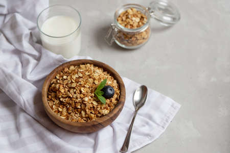 Top view on a wooden bowl with freshly prepared granola or oatmeal granola and a glass of milk nearby. Healthy breakfast at home for children.の写真素材
