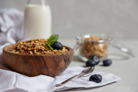 Muesli or oatmeal granola in a wooden bowl next to a bottle of fresh milk and berries. Proper nutrition, healthy breakfastの写真素材