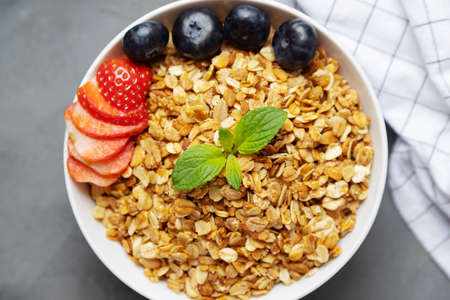 Top view on a plate of homemade granola, oatmeal granola, decorated with berries and mint. Proper nutrition, home cooked food.の写真素材