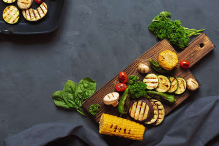 Grilled vegetables on a wooden cutting board. The concept of vegetarian grill menu. Place for text. Dark backgroundの写真素材