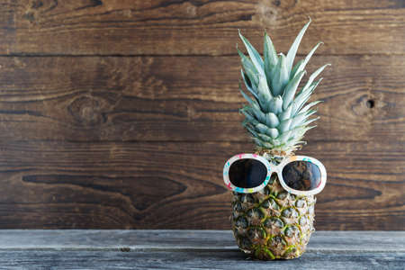 Conceptual vacation, tourism, travel tropical fruit, pineapple in sunglasses in the background. Copy space.の写真素材