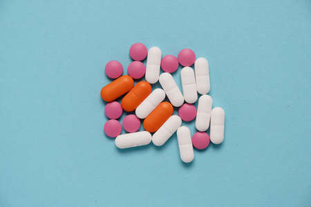 A handful of tablets or pills or antibiotics, pink, orange and white. Medical concept of taking medication. Pharmacologyの写真素材