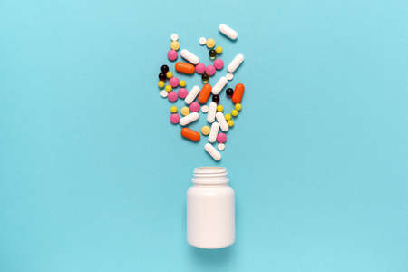 multi-colored tablets, capsules, medicines, pills spilled out of a white jar or bottle, bottle. Medical concept. Place for textの写真素材