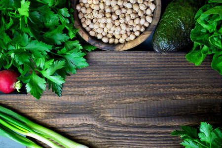 Green vegetables and lentils around a rustic of wooden cutting board. Place for text. Cooking healthy bio food in the kitchen at home. Salad Ingredients.の写真素材