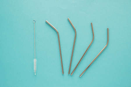 Reusable iron tubules for cocktails, drinks and juices and a brush for washing on a blue background....