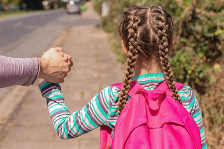 Back to school. Close-up A dad, father or parent is seeing off or leading his daughter with a backpack or knapsack to school down the street and holding her hand. first day of school, new school yearの写真素材