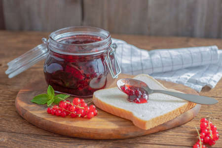Homemade red currant jam in a glass jar. Toast or bread with marmalade for breakfast. Preparations...