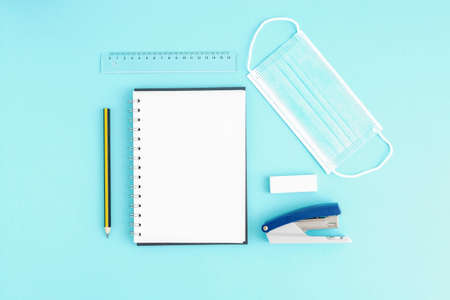 Blank open notebook with blank sheets and around stationery and medical protective mask, stapler,...