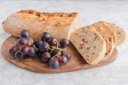 An overhead view of a fresh and crispy cut ciabatta with raisins and grape twigs. Homemade italian bread, bakeryの写真素材
