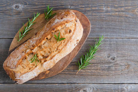 Homemade fresh bread. Italian traditional ciabatta on wooden board with rosemary sprigs