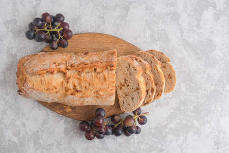 An overhead view of a fresh and crispy cut ciabatta with raisins and grape twigs. Homemade italian...