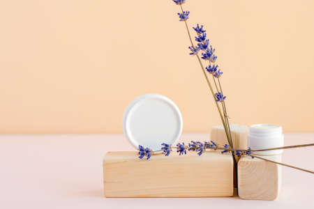 A white jar of face or body cream on a trendy wooden cube next to dried lavender flowers. The concept of natural natural care cosmetics. Place for text.の写真素材