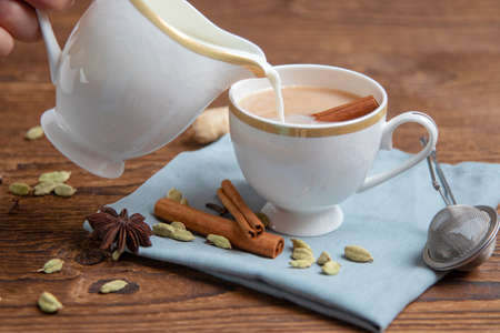 Preparation of traditional Indian tea masala on wooden background. Winter hot drink made from tea with milkの写真素材