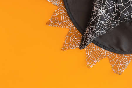 Halloween flat lay with a sorceress hat. Top view of a witch's hat on an orange background. Place...