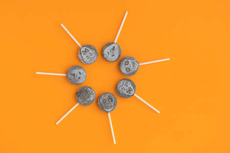 Creepy sucking candy or skull-shaped lollipops lie in a circle. Design element, Halloween background. Orange background. Place for text.の写真素材