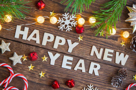 Wooden letters Happy New Year on a wooden background with branches of Christmas trees, garlands and New Year's toys. Ideal for a greeting cardの写真素材