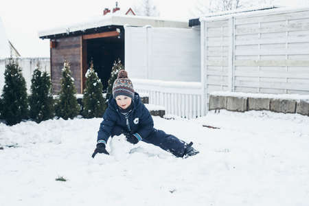 Games in the snow, winter holidays, family vacations. Cute caucasian boy playing in the snow in the...