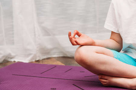 The girl practices yoga at home. Relaxation and meditation for children and adults. Place for text