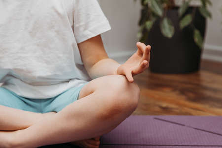 The girl practices yoga at home. Relaxation and meditation for children and adults. Place for textの写真素材