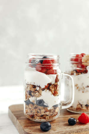 A healthy, dietary breakfast or snack of granola or oatmeal muesli with yoghurt and fresh wild berries. Light background and vertical photo. Copy spaceの写真素材