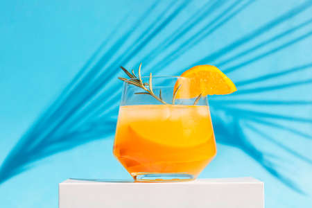 orange cocktail, juice, a drink in a glass glass stands on the podium with the shadow of a palm...