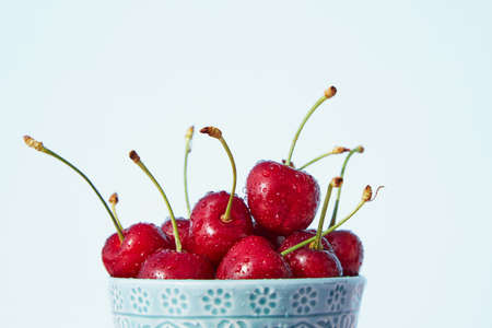 Close-up of fresh cherries with splashing water in a blue bowl. Fresh bio organic seasonal fruits...
