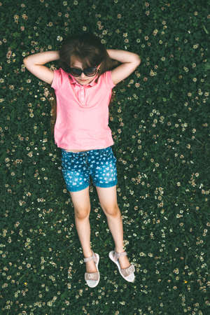 A cute teenage girl lies on a blooming meadow of clover with her eyes closed. Holidays, summer...