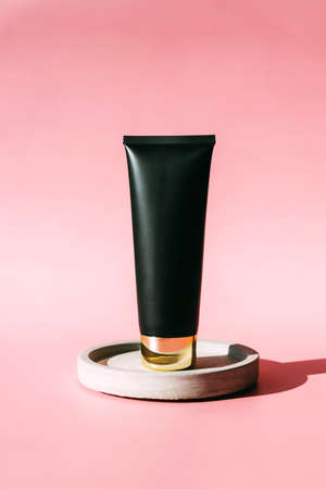 Cosmetic mock ap. Black tube with cream, face mask, scrub on a concrete stand on a pink background. Skin careの写真素材