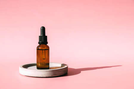 A jar of serum, hiauloronic acid, collagen or retinol for facial skin care stands on a concrete podium against a pastel pink background. Copy spaceの写真素材