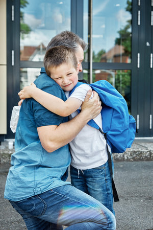Back to school. Dad sees off, hugs the child before the start of lessons. The new school year. Caring, parent-child relationshipの写真素材