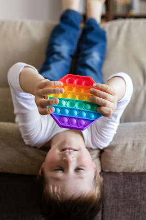 Trendy silicone toy anti stress , simple dimple. The boy is at home on the couch. Kids toysの写真素材