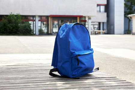 Back to school. A blue backpack, a schoolbag on a bench in the schoolyard. The beginning of the...